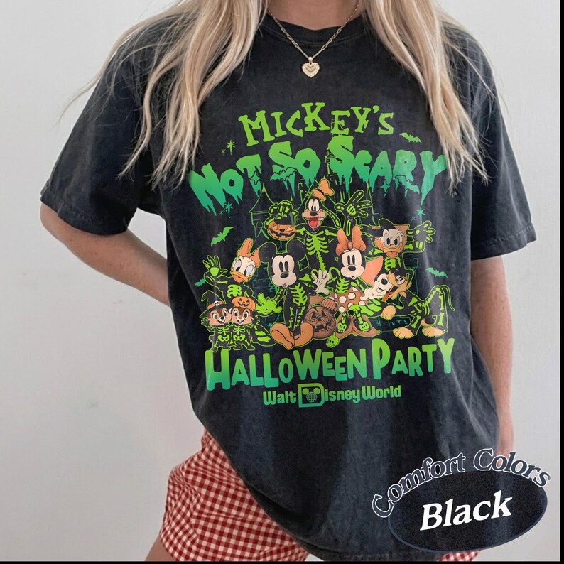 K&ouml;nnte beinhalten: Schwarzes T-Shirt mit einer gr&uuml;n-wei&szlig;en Grafik mit Disney-Figuren in Skelett-Kost&uuml;men. Der Text lautet "Mickey's Not So Scary Halloween Party" und "Walt Disney World". Das Shirt ist mit "Comfort Colors Black" gekennzeichnet.