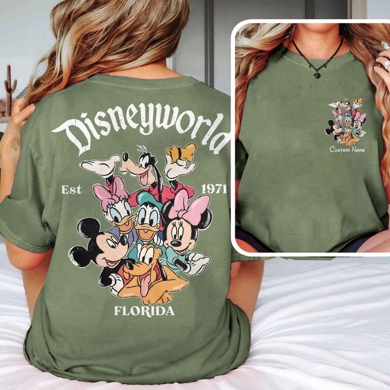 May include: Olive green t-shirt featuring a Disney World graphic with Mickey Mouse, Minnie Mouse, Donald Duck, Daisy Duck, Goofy, and Pluto. The back of the shirt displays "Disneyworld Florida Est 1971". The front has a smaller graphic and the text "Custom Name".