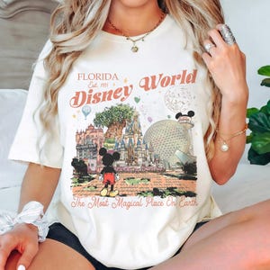 May include: A white ceramic mug with a black handle and the text "But first, coffee" in a black, handwritten-style font. The mug is on a white surface.