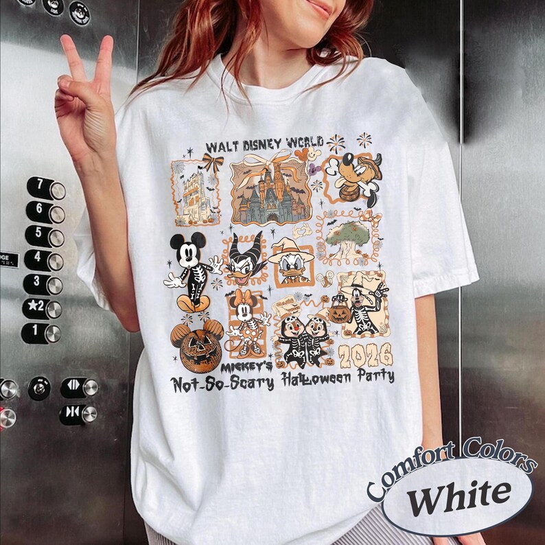 Pu&ograve; includere: T-shirt bianco con una grafica colorata di personaggi Disney in costume di Halloween. Il design include il testo "Walt Disney World" e "Mickey's Not-So-Scary Halloween Party 2026". La maglietta &egrave; etichettata "Comfort Colors White".