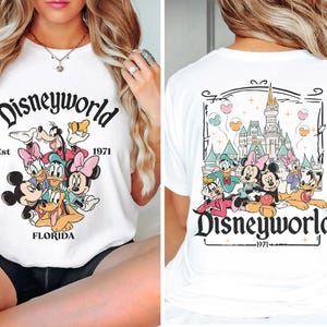 Puede incluir: Camiseta blanca con un estampado gr&aacute;fico de Mickey Mouse y sus amigos frente al Castillo de Cenicienta. El texto "Disneyworld Est 1971" est&aacute; impreso en la camiseta.