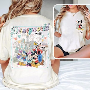 Pu&ograve; includere: T-shirt color crema con una grafica colorata di Disney World 2026 sul retro con personaggi dei cartoni animati. La parte anteriore presenta una grafica pi&ugrave; piccola di Mickey Mouse con la scritta "Dad" sotto. La maglietta ha maniche corte.