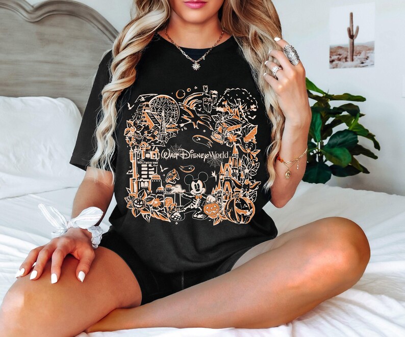 May include: Black t-shirt with a graphic print of various Halloween-themed Disney characters and attractions. The text "Walt Disney World" is featured on the shirt.