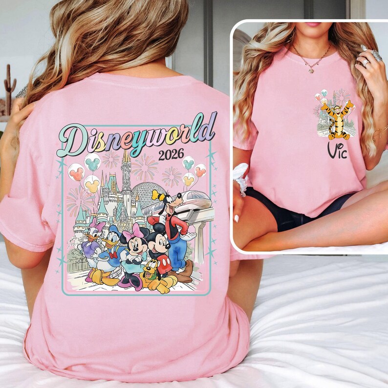 Pu&ograve; includere: T-shirt rosa chiaro con un disegno di Disney World 2026 sul retro, con Topolino, Minnie, Paperino, Paperina, Pippo e Pluto. Il davanti mostra Tigro e il nome "Vic".