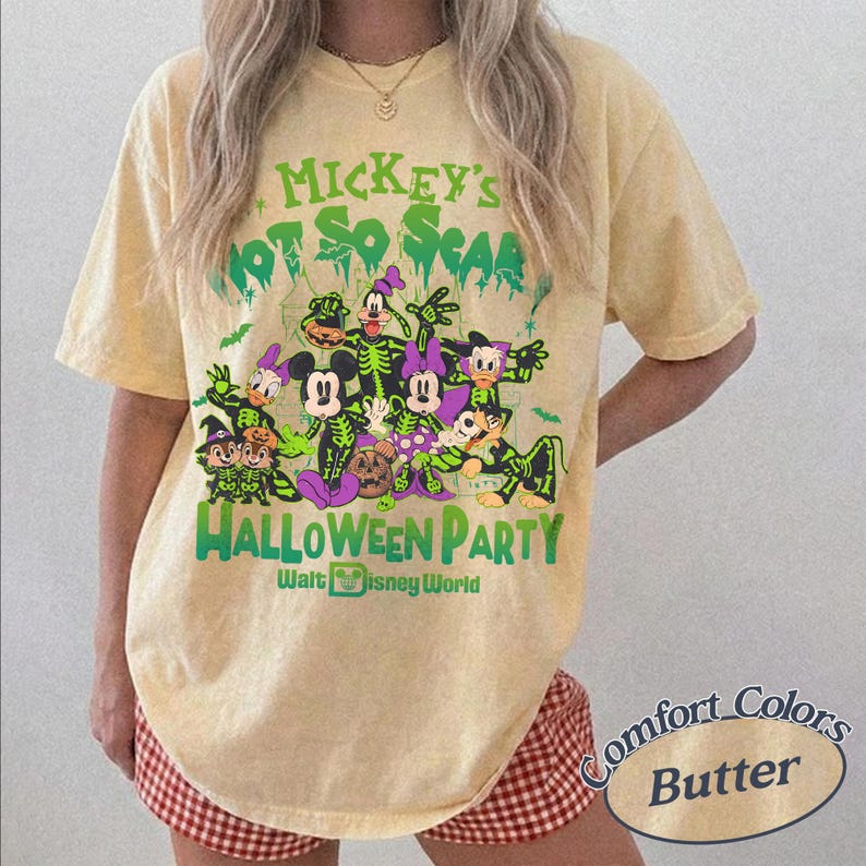 Op de afbeelding: Een lichtgeel t-shirt met een Halloween-thema met Disney-personages in skeletkostuums. De tekst op het shirt luidt "Mickey's Not So Scar Halloween Party" en "Walt Disney World". Het shirt is een Comfort Colors Butter.