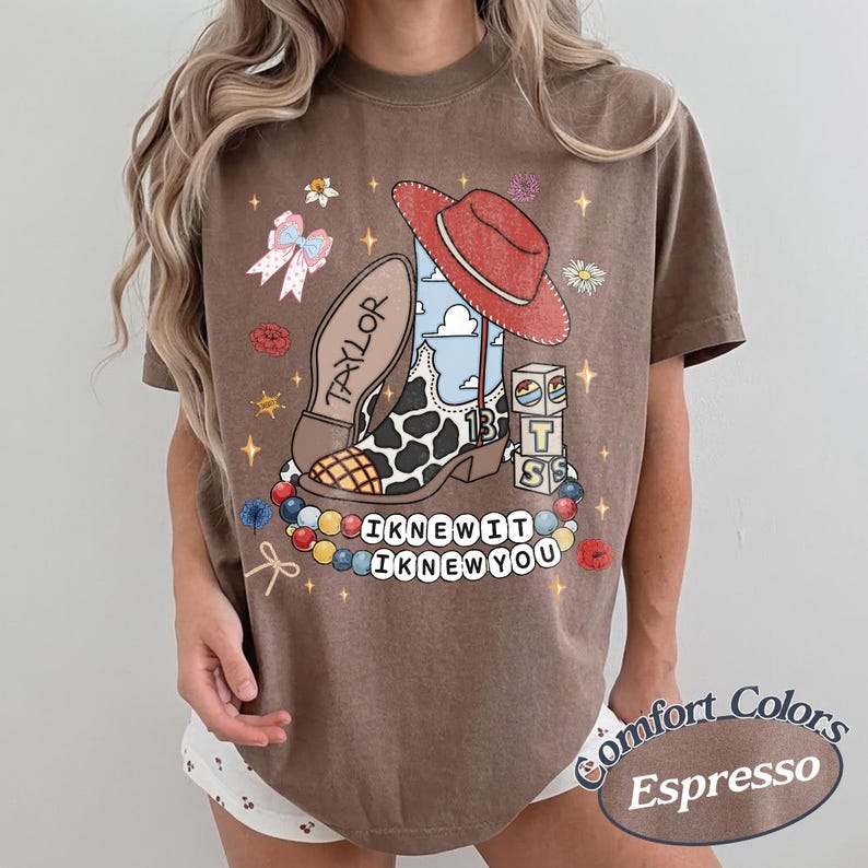 May include: A brown short-sleeve t-shirt featuring a graphic print of a cowboy boot with a cow print pattern, a red hat, building blocks with the letters T, S, and a cloud design, a bow, and beads. The text reads Taylor, 13, I KNEW IT, I KNEW YOU.
