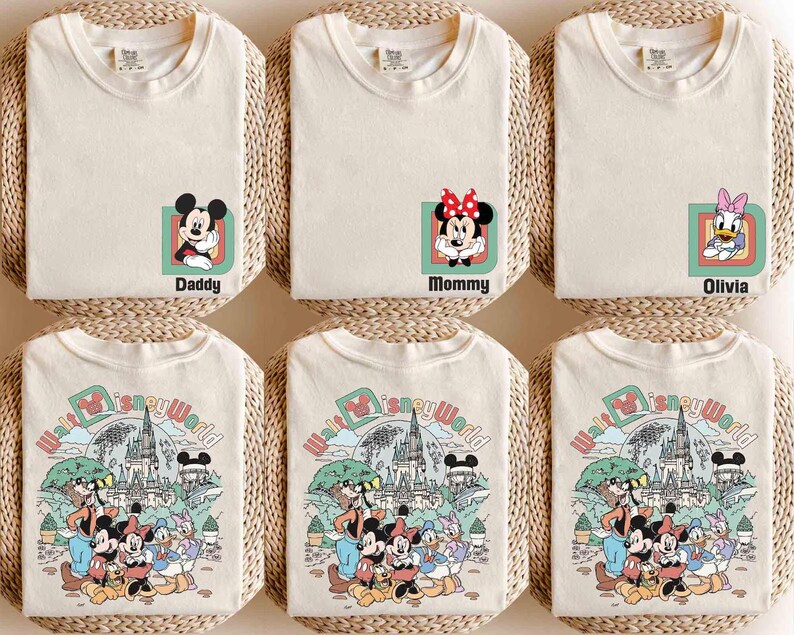 Puede incluir: Camisetas color crema con personajes de Disney y texto. Una camiseta tiene a Mickey Mouse con "Daddy", otra a Minnie Mouse con "Mommy", y una tercera a Daisy Duck con "Olivia". Las camisetas inferiores muestran un gr&aacute;fico colorido de Disney World.