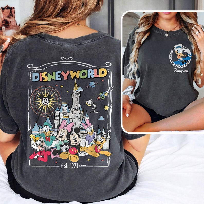 Op de afbeelding: Donkergrijs T-shirt met een Disney World-afbeelding op de achterkant, met Mickey Mouse, Minnie Mouse, Donald Duck, Daisy Duck en Pluto. De voorkant heeft een kleine Donald Duck-afbeelding en het woord "Brother".