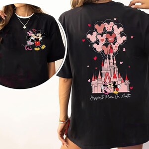 May include: Black t-shirt featuring a colorful graphic of Mickey and Minnie Mouse in front of a castle, with heart-shaped balloons and the text "Happiest Place On Earth". The front of the shirt shows Mickey and Minnie Mouse.