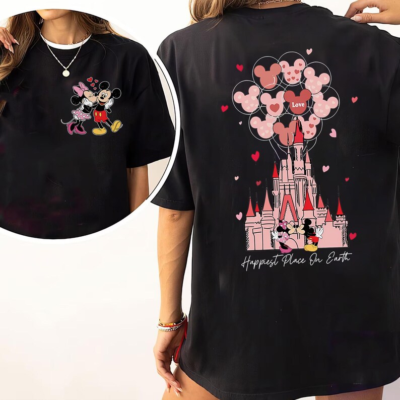 May include: Black t-shirt featuring a colorful graphic of Mickey and Minnie Mouse in front of a castle, with heart-shaped balloons and the text "Happiest Place On Earth". The front of the shirt shows Mickey and Minnie Mouse.