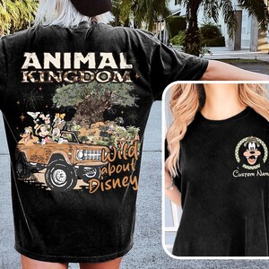 May include: Black t-shirt featuring a graphic of Mickey Mouse and friends in a brown jeep with the text "Animal Kingdom" and "Wild About Disney". A smaller image of Mickey Mouse is on the front.