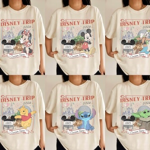 Pu&ograve; includere: T-shirt color crema con personaggi Disney, tra cui Topolino e Minnie. Ogni maglietta mostra "DISNEY TRIP 2024" sopra il personaggio, con spazio per un nome personalizzato. Stile casual.