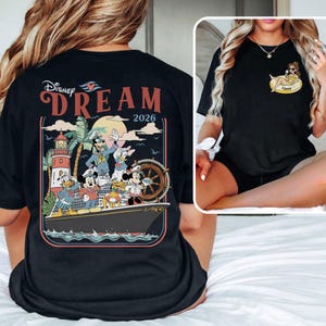 May include: Black t-shirt with a Disney Dream cruise design. The back graphic shows Mickey Mouse, Donald Duck, Goofy, and other characters on a ship, with a lighthouse and the year 2026. The front has a small graphic of a character.