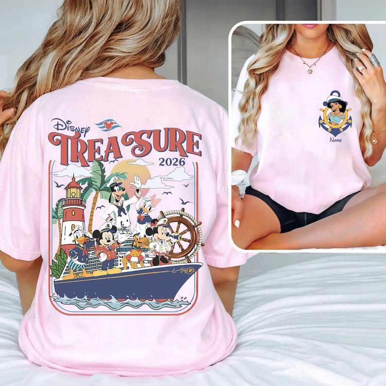 May include: Light pink t-shirt featuring a Disney Treasure design with various characters on a ship, including Mickey Mouse, Donald Duck, and Goofy. The back of the shirt has the words "Disney Treasure 2026". The front of the shirt has a Jasmine anchor design.