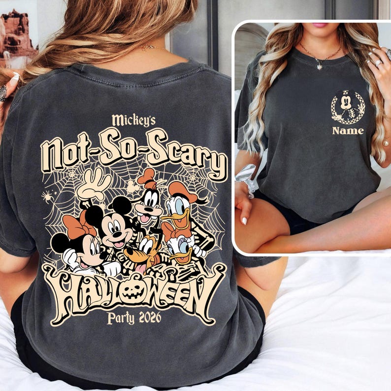 May include: Dark gray t-shirt featuring a Halloween design with Mickey Mouse, Minnie Mouse, Goofy, Donald Duck, and Pluto. The shirt has the text "Mickey's Not-So-Scary Halloween Party 2026" in a stylized font. A smaller image on the front shows a Mickey Mouse head.