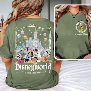Puede incluir: Camiseta verde oliva con un dise&ntilde;o de Disney World. El dise&ntilde;o incluye personajes de Disney, un castillo y el texto "Disneyworld Family Trip 2026." Una imagen m&aacute;s peque&ntilde;a en la camiseta muestra a Pluto con el texto "Custom Name."