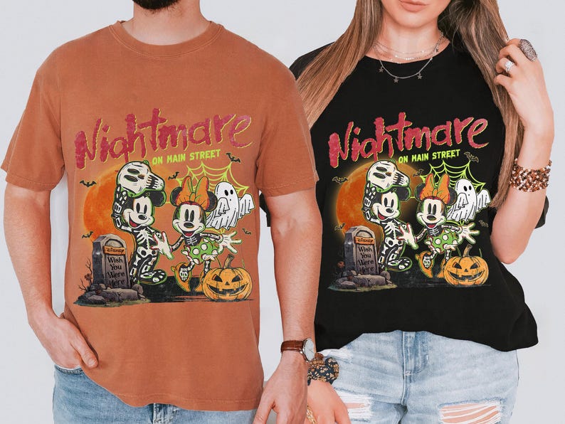 May include: Two t-shirts, one orange and one black, featuring a Halloween-themed graphic. The design includes Mickey and Minnie Mouse dressed as skeletons, a pumpkin, and the text "Nightmare on Main Street."