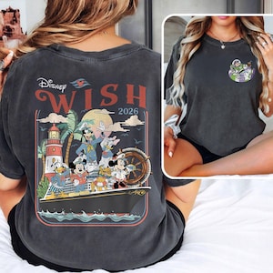 May include: Dark grey t-shirt with a graphic of Disney characters on a cruise ship, including Mickey Mouse and Donald Duck, with the text "Disney Wish 2026." A smaller Buzz Lightyear graphic is on the front. The design has a vintage aesthetic.