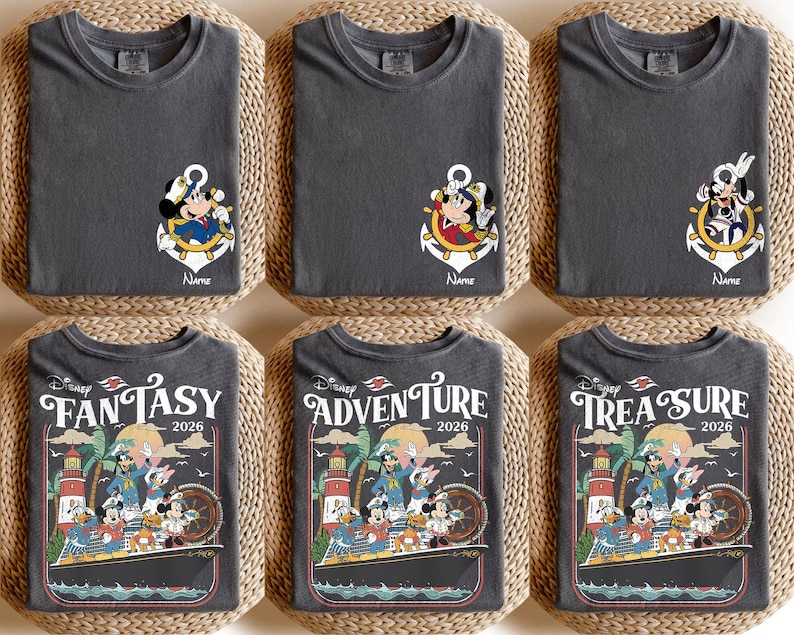 Puede incluir: Seis camisetas de color gris oscuro con dise&ntilde;os de personajes de Disney. Tres camisetas presentan a Mickey Mouse en un dise&ntilde;o de ancla, con la palabra "Name" debajo. Las otras tres camisetas tienen un dise&ntilde;o de crucero con las palabras "Fantasy 2026", "Adventure 2026" y "Treasure 2026".