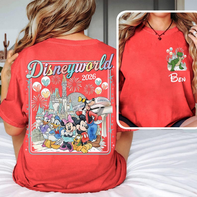Pu&ograve; includere: Maglietta rossa con personaggi Disney e la scritta "Disneyworld 2026". Il retro presenta una grafica colorata del castello Disney, fuochi d'artificio e personaggi. Il davanti ha una grafica di dinosauro con il nome "Ben".