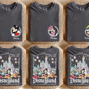 May include: Set of six gray t-shirts featuring Disney characters and the text "Disneyland" with a castle graphic. The shirts are designed for a family with a "Daddy", "Mommy", and four children.
