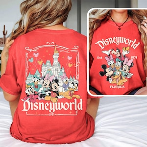 Puede incluir: Camiseta roja con un gr&aacute;fico de Mickey Mouse y sus amigos frente al Castillo de Cenicienta. El texto "Disneyworld Est 1971 Florida" est&aacute; impreso en la camiseta.