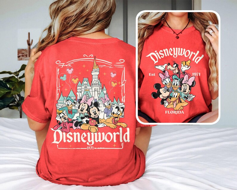 Puede incluir: Camiseta roja con un gr&aacute;fico de Mickey Mouse y sus amigos frente al Castillo de Cenicienta. El texto "Disneyworld Est 1971 Florida" est&aacute; impreso en la camiseta.