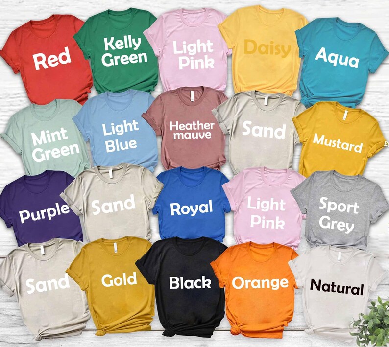 May include: A collection of short-sleeved t-shirts in various colors, including red, green, pink, yellow, and blue. Each shirt displays a color name in white block letters. The shirts are neatly arranged, showcasing a range of hues.