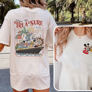 May include: Cream-coloured t-shirt with a Disney cruise design. The back graphic shows Mickey Mouse, Donald Duck, and Goofy on a ship with the text "Disney Treasure 2026." A smaller graphic of Mickey Mouse on a float is on the front.