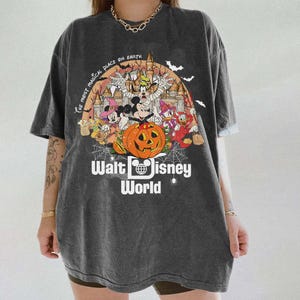 May include: A dark gray t-shirt with a Halloween-themed graphic featuring Mickey Mouse and other Disney characters. The graphic includes a pumpkin, a castle, and the text "The Most Magical Place on Earth" and "Walt Disney World".