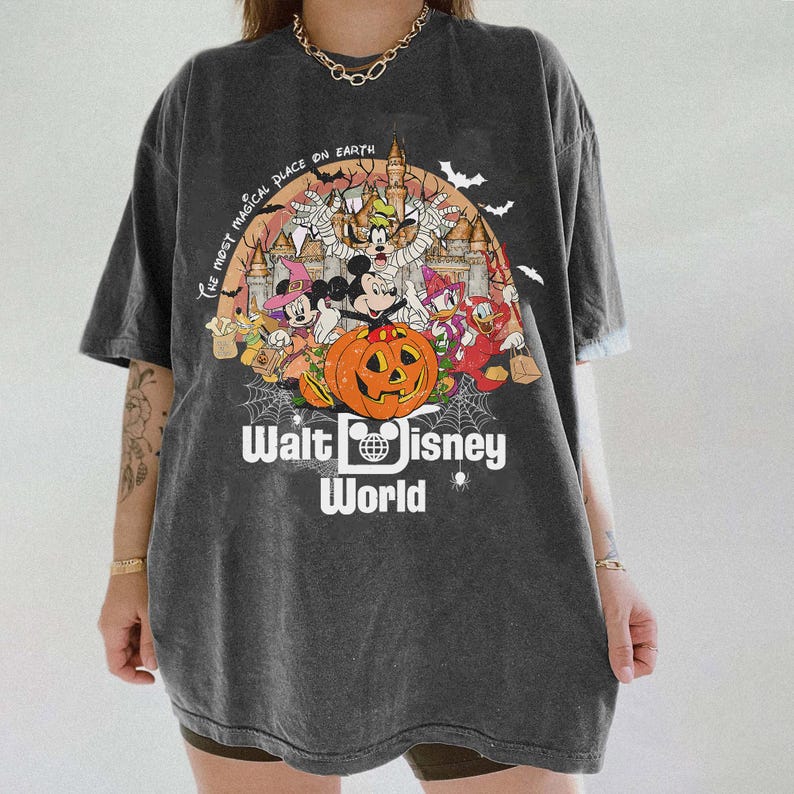 May include: A dark gray t-shirt with a Halloween-themed graphic featuring Mickey Mouse and other Disney characters. The graphic includes a pumpkin, a castle, and the text "The Most Magical Place on Earth" and "Walt Disney World".