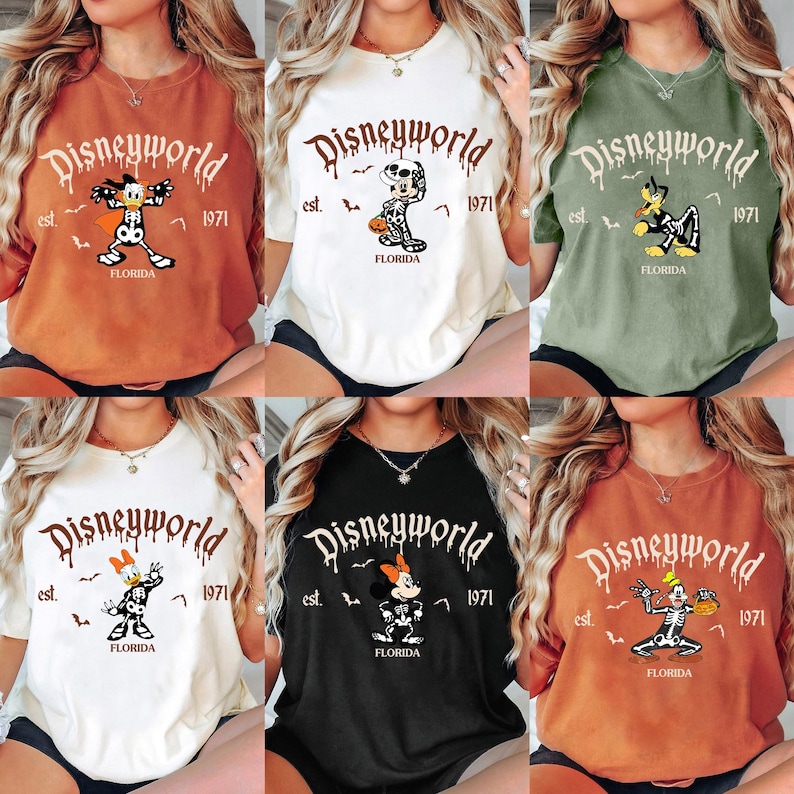 Op de afbeelding: Zes T-shirts in verschillende kleuren, elk met een "Disneyworld"-afbeelding met een stripfiguur in een skeletkostuum. De shirts bevatten de tekst "est. 1971" en "Florida".