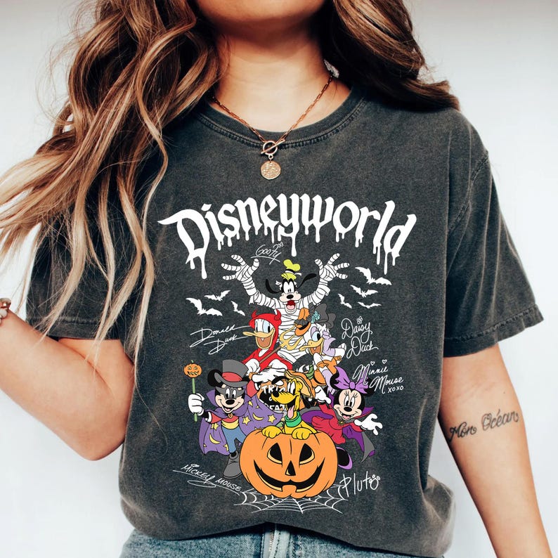 May include: Dark gray t-shirt featuring a Halloween-themed Disney World graphic. The design includes Disney characters dressed in costumes, a carved pumpkin, bats, and the text "Disneyworld".