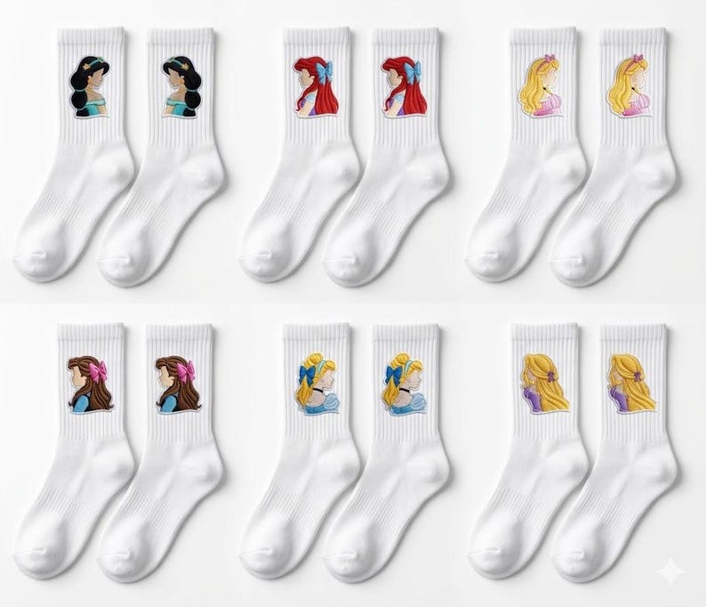May include: White crew socks with embroidered portraits of animated princesses. Each sock features a different princess, with details like hair colour and accessories. The socks are arranged in pairs, showcasing various princess designs.