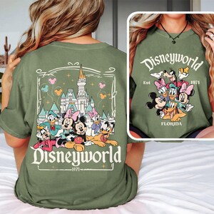 Puede incluir: Camiseta verde con un gr&aacute;fico de Mickey Mouse y sus amigos frente al Castillo de Cenicienta. El texto "Disneyworld Est. 1971 Florida" est&aacute; impreso en la camiseta.