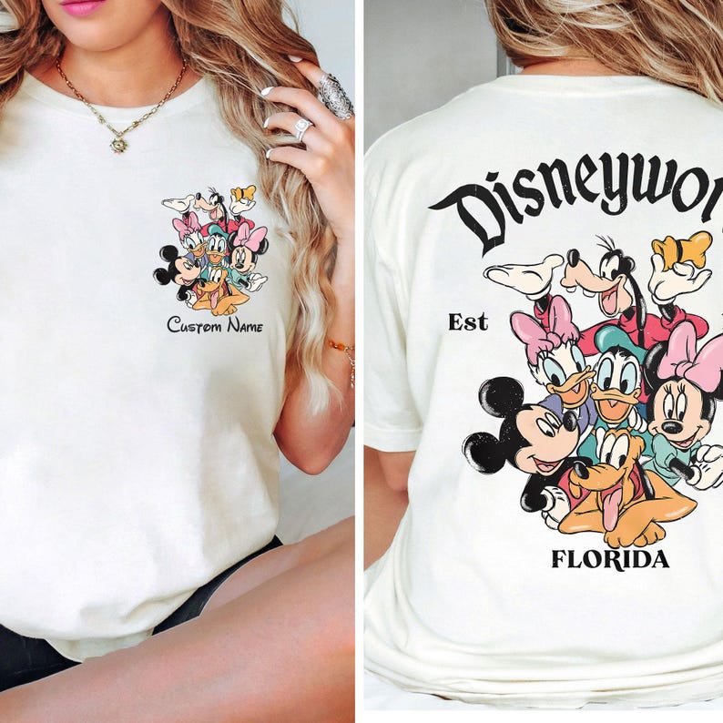 May include: Cream-colored t-shirt featuring a Disney character graphic on the front and back. The front graphic includes Mickey, Minnie, Donald, Daisy, Goofy, and Pluto with the text "Custom Name." The back graphic says "Disneyworld Florida Est."