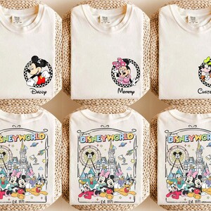 Op de afbeelding: Off-white T-shirts met Disney-personage afbeeldingen. E&eacute;n shirt toont Mickey Mouse met "Daddy", een ander Minnie Mouse met "Mommy", en een derde met Goofy en "Custom Name". De onderste shirts tonen een Disney World ontwerp.