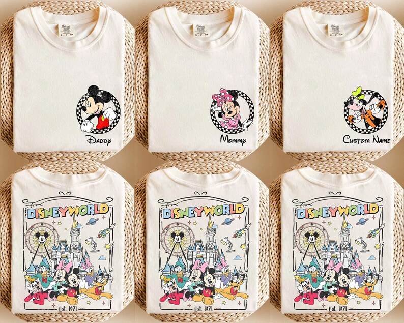 Op de afbeelding: Off-white T-shirts met Disney-personage afbeeldingen. E&eacute;n shirt toont Mickey Mouse met "Daddy", een ander Minnie Mouse met "Mommy", en een derde met Goofy en "Custom Name". De onderste shirts tonen een Disney World ontwerp.