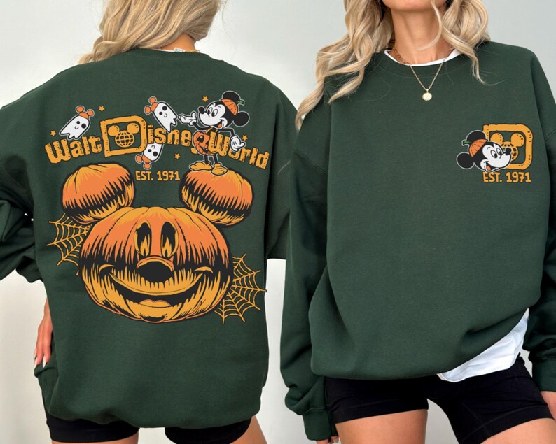 May include: Dark green sweatshirt featuring a Halloween-themed design. The front displays a Mickey Mouse graphic with "Est. 1971". The back has a large jack-o'-lantern, Mickey Mouse, ghosts, and the words "Walt Disney World".