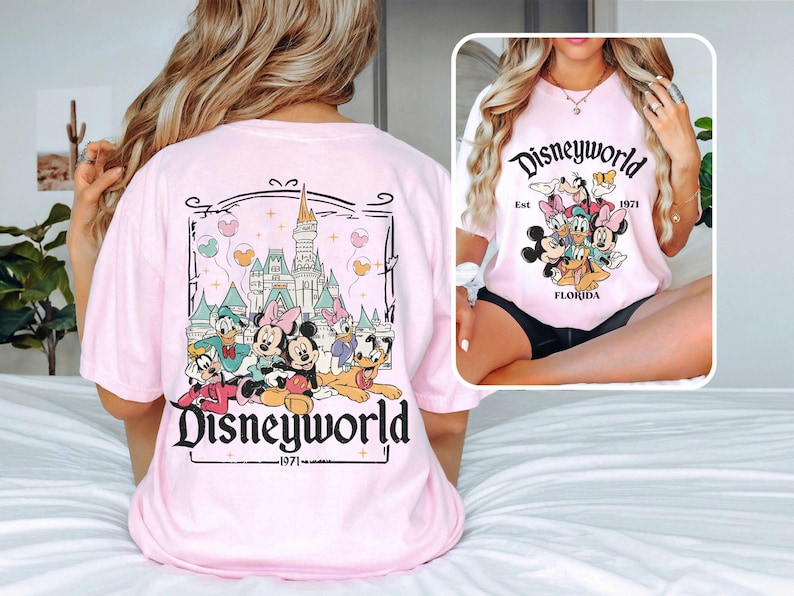 Puede incluir: Camiseta rosa con un gr&aacute;fico de Mickey Mouse y sus amigos frente al Castillo de Cenicienta. El texto "Disneyworld Est. 1971 Florida" est&aacute; impreso en la camiseta.
