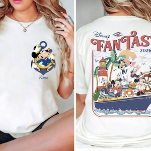 May include: Cream-colored t-shirt featuring a cartoon Mickey Mouse as a ship captain, with an anchor and the word "Name" below. The back of the shirt displays "Disney Fantasy 2026" with various Disney characters on a cruise ship.