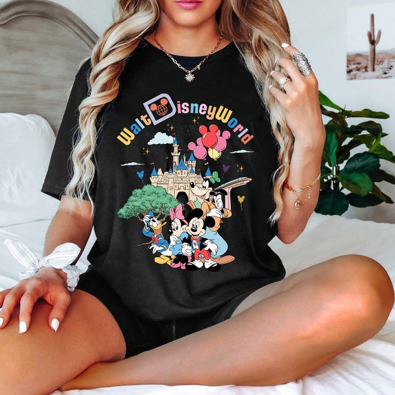 May include: Black t-shirt with a graphic print of Mickey Mouse and friends in front of Cinderella's Castle. The text "Walt Disney World" is printed in rainbow colors.