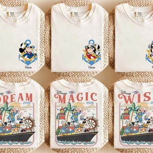 May include: Off-white t-shirts with Disney character designs. Some shirts feature Mickey Mouse in an anchor, while others display a cruise ship scene with Mickey and friends. The shirts have the words "Dream", "Magic", and "Wish" with the year 2026.