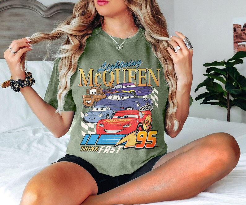 May include: Green t-shirt with a graphic of Lightning McQueen and other cars from the Cars movie. The text "Lightning McQueen" and "Think Fast" are printed on the shirt.
