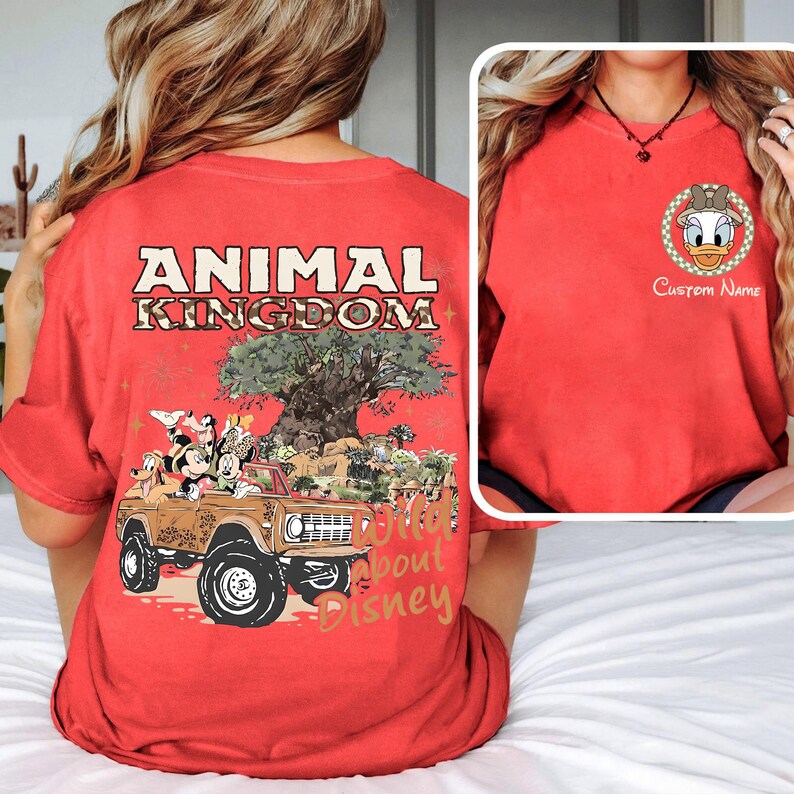 May include: Red t-shirt with a graphic of a brown jeep with Disney characters and the text "ANIMAL KINGDOM" and "Wild about Disney". A smaller image shows a Daisy Duck graphic with the text "Custom Name".
