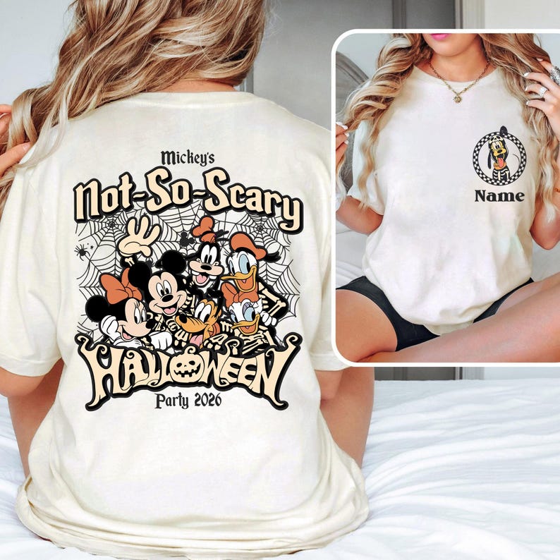 May include: Cream-colored t-shirt featuring a graphic of Disney characters, including Mickey and Minnie Mouse, Donald Duck, and Goofy, with the text "Mickey's Not-So-Scary Halloween Party 2026". The shirt also has a smaller graphic of Pluto.
