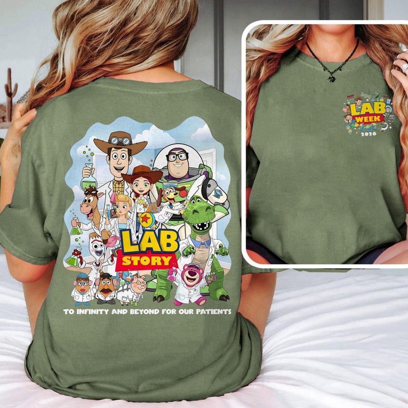 May include: Olive green t-shirt featuring a colorful graphic of Toy Story characters in lab coats with the words "LAB STORY" and "TO INFINITY AND BEYOND FOR OUR PATIENTS." A smaller graphic on the front reads "LAB WEEK 2016."