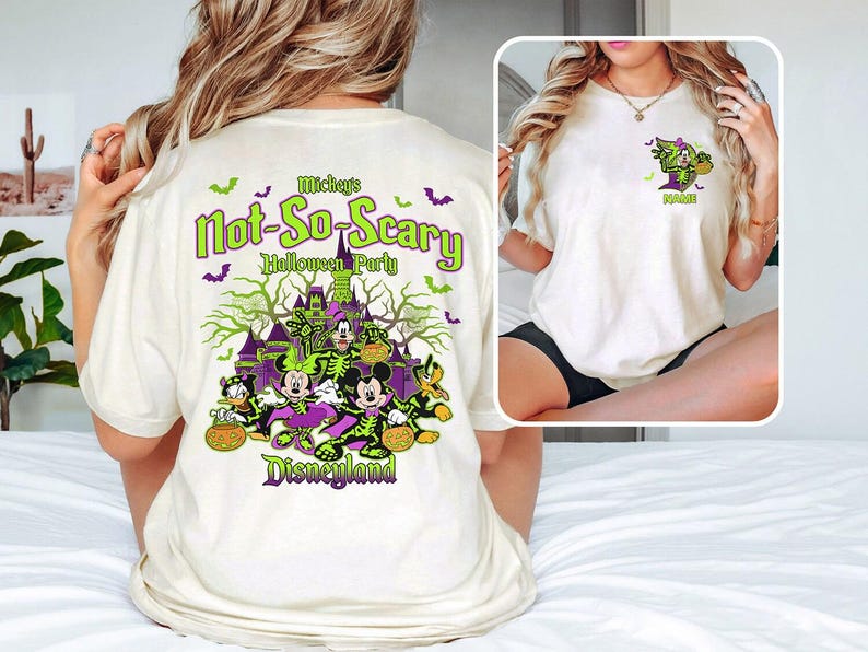 May include: Cream-colored t-shirt featuring a Halloween-themed graphic. The design includes the text "Mickey's Not-So-Scary Halloween Party Disneyland" in green and purple, along with images of Disney characters in Halloween costumes.