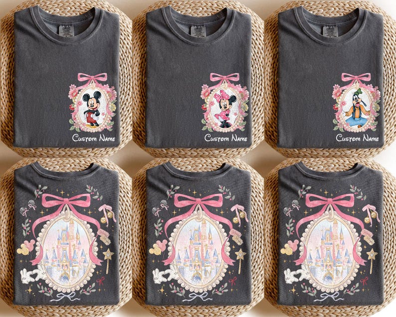 Pode incluir: Seis camisetas cinza carv&atilde;o com diferentes designs. Algumas camisetas apresentam Mickey Mouse, Minnie Mouse e Pateta em molduras ovais com detalhes florais e la&ccedil;os. Outras camisetas exibem um design de castelo com um la&ccedil;o rosa e o texto "Custom Name".
