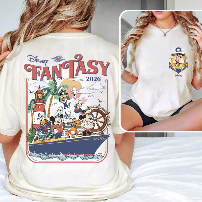 May include: Cream-colored t-shirt featuring a Disney cruise design. The back graphic includes the words "Disney Fantasy 2026" with Mickey Mouse, Donald Duck, and Goofy on a ship. The front has an anchor with Woody.